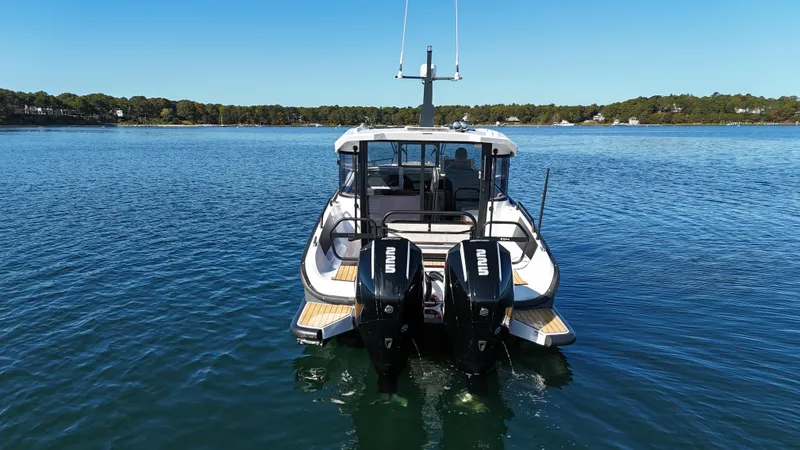 Slide: The Image of 2023 XO Boats EXPLR 10 Sport Plus on calm water, rear view with dual engines. - 4