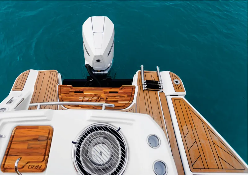 Slide: The Image of NHD 255 Open Deck 2025 boat with teak flooring and outboard motor on blue water. - 6