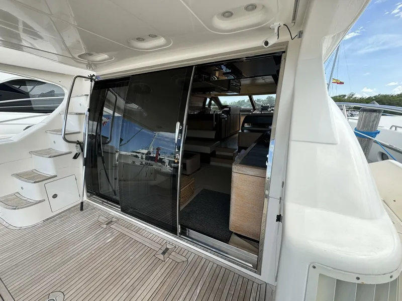 Slide: The Image of 2013 Azimut 64 Fly yacht interior view with sliding glass doors and wooden deck. - 8