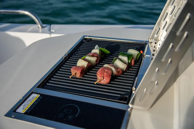 Slide: The Image of Grilling kebabs on MJM 35 boat, 2025 model, with ocean backdrop. - 21