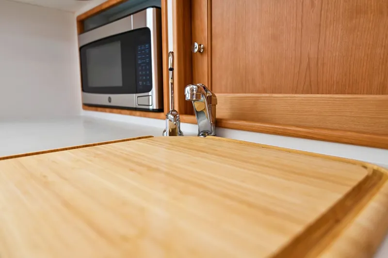 Slide: The Image of Modern kitchen area in MJM 35 boat, featuring a microwave and wooden countertop, 2025 model. - 35
