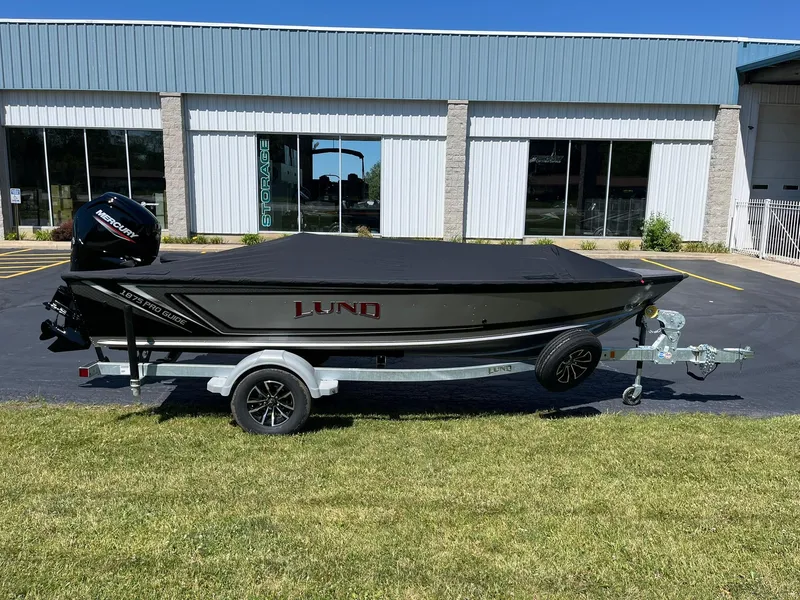 Slide: The Image of 2025 Lund 1875 Pro Guide fishing boat on a trailer, covered and parked outside. - 5