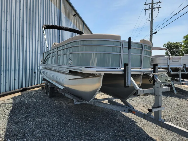 Slide: The Image of 2025 Harris Cruiser 230 pontoon boat on a trailer outside a metal building. - 3