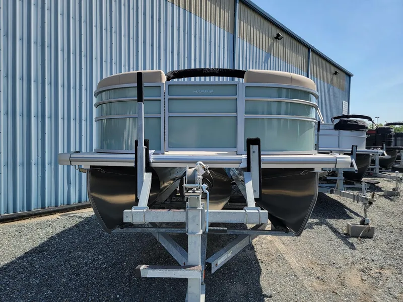 Slide: The Image of 2025 Harris Cruiser 230 pontoon boat on a trailer, parked outside a metal building. - 4