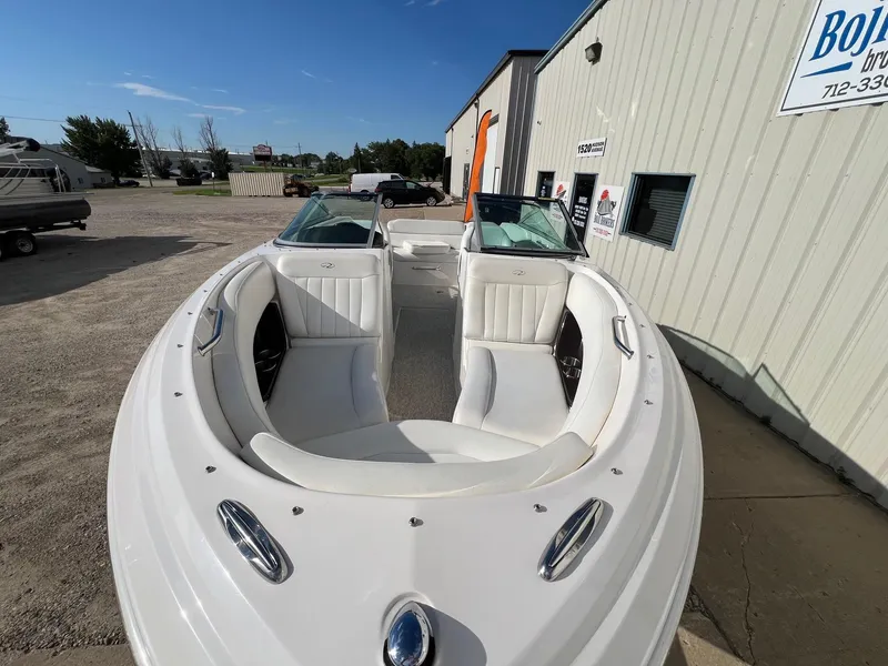 Slide: The Image of 2006 Regal 2200 Bowrider boat with white interior, parked outside a building. - 3
