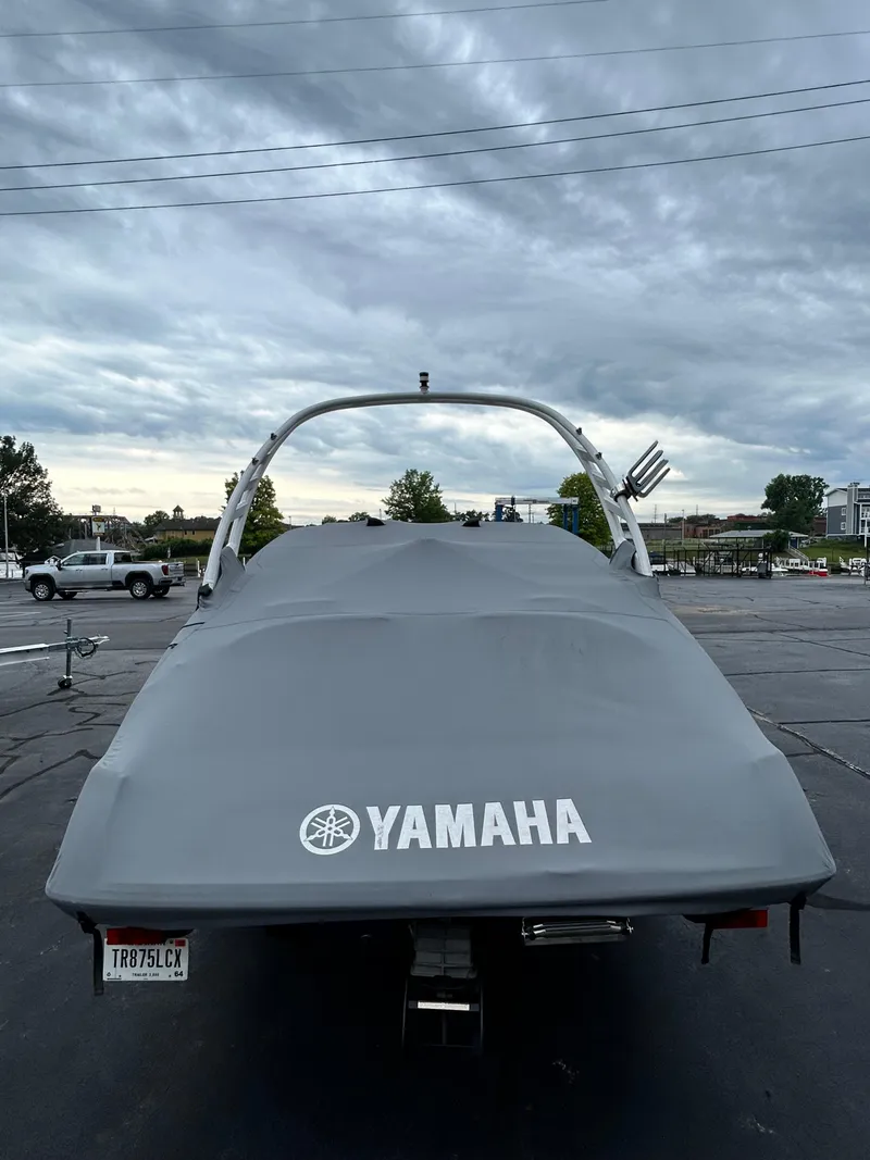 Slide: The Image of 2022 Yamaha Boats 195 S covered and parked in a lot under a cloudy sky. - 10