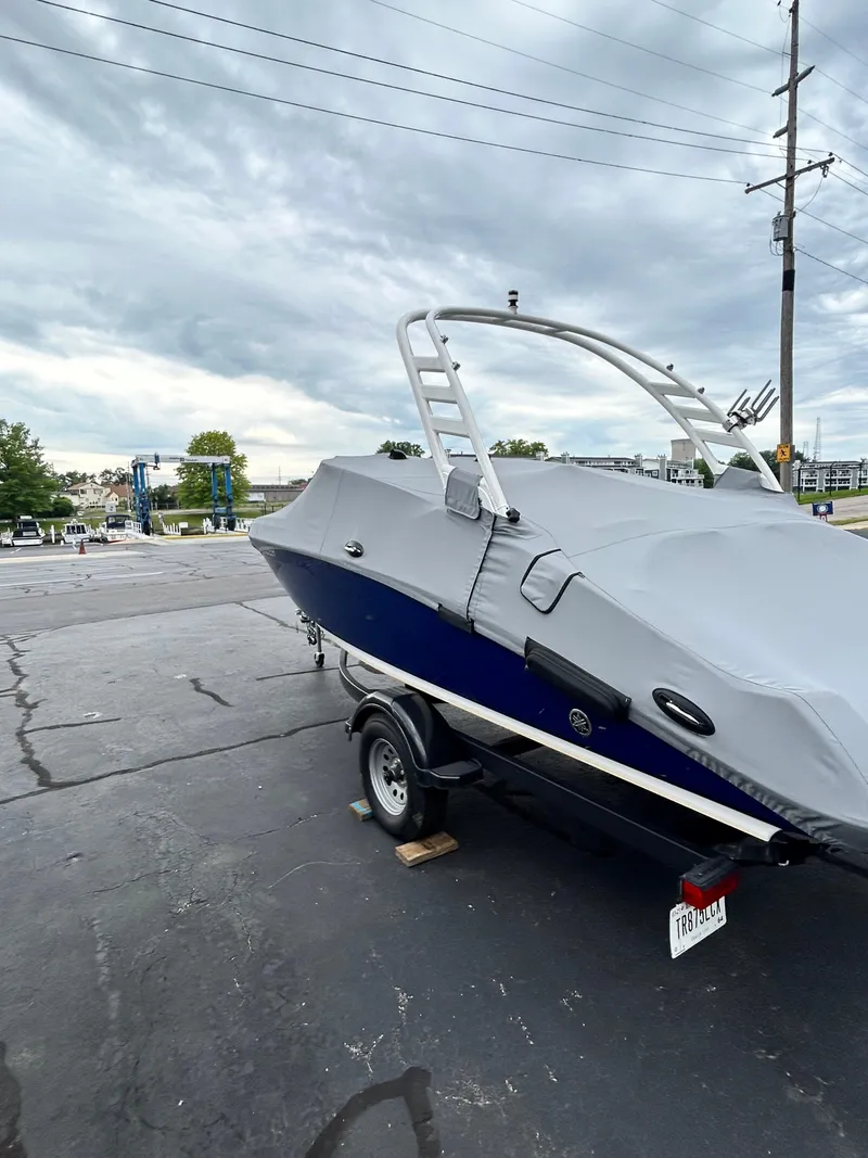 Slide: The Image of 2022 Yamaha Boats 195 S covered and parked on a trailer in a lot. - 11
