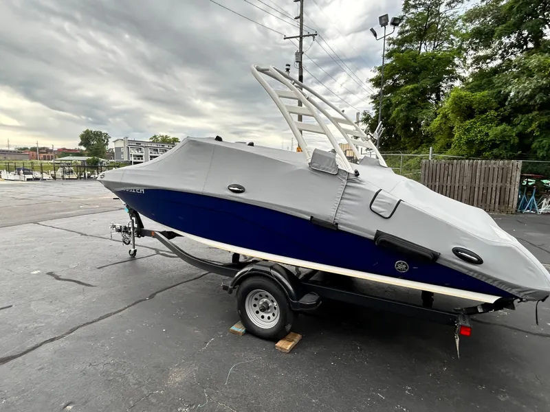 Slide: The Image of 2022 Yamaha Boats 195 S with cover on trailer, parked outdoors. - 12