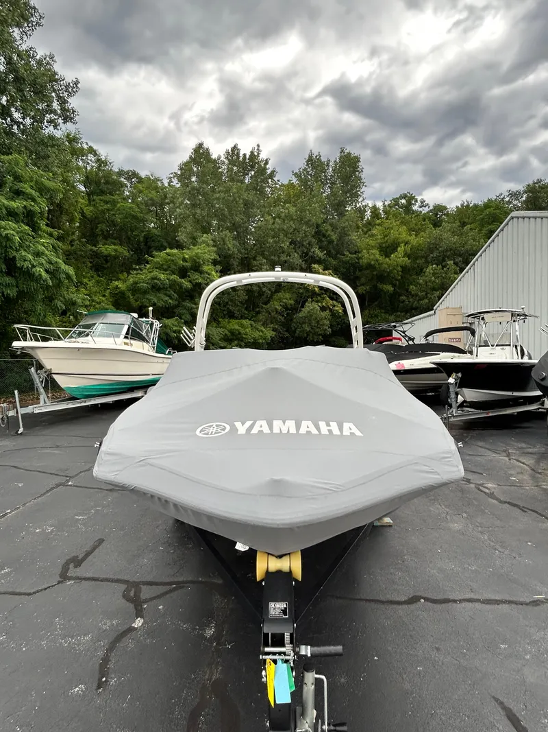 Slide: The Image of 2022 Yamaha Boats 195 S with cover in a boatyard. - 13