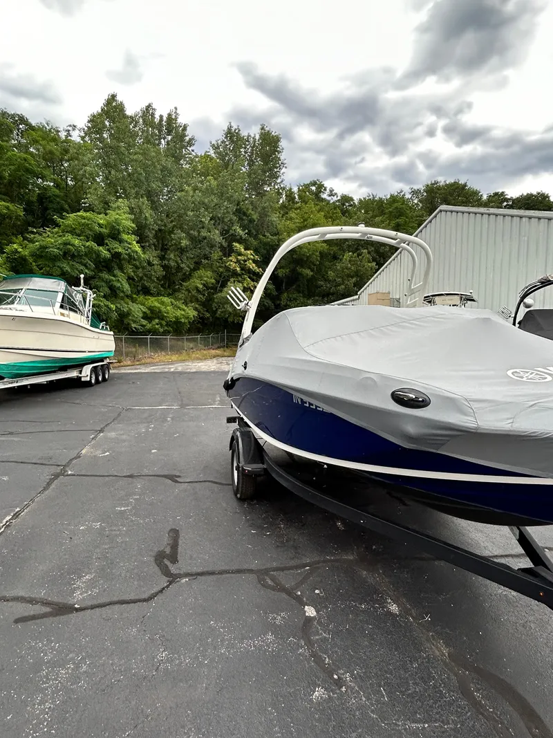 Slide: The Image of 2022 Yamaha Boats 195 S covered and parked on a paved lot. - 14