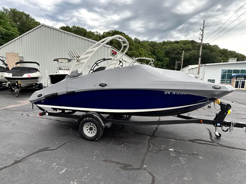 Slide: The Image of 2022 Yamaha Boats 195 S with cover on trailer in parking lot. - 15