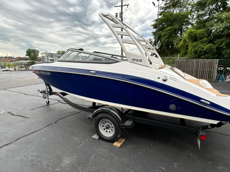 Slide: The Image of 2022 Yamaha Boats 195 S in blue on a trailer, parked outdoors. - 16