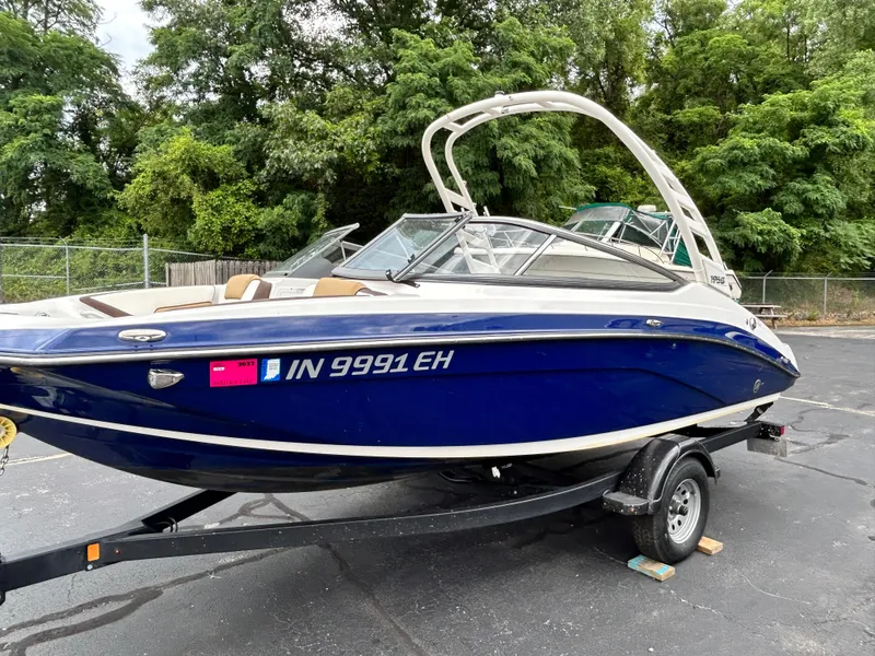 Slide: The Image of 2022 Yamaha Boats 195 S on trailer, blue hull, parked outdoors. - 18