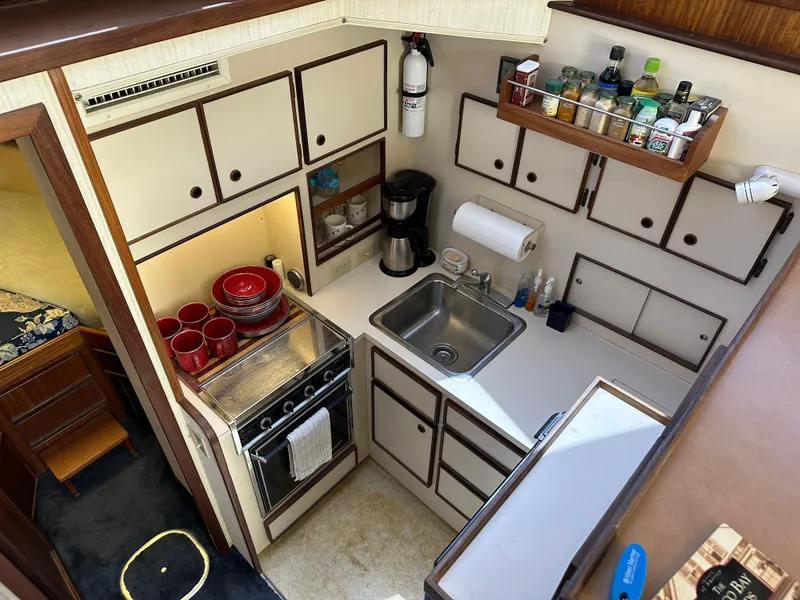 Slide: The Image of 1985 Hatteras 36 Convertible kitchen with stove, sink, and storage cabinets. - 16