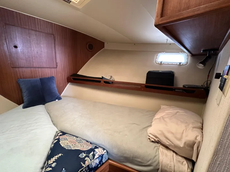 Slide: The Image of 1985 Hatteras 36 Convertible cabin with twin beds and wooden storage shelves. - 25