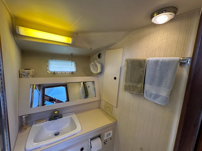 Slide: The Image of 1985 Hatteras 36 Convertible bathroom with sink, mirror, and towels. - 29