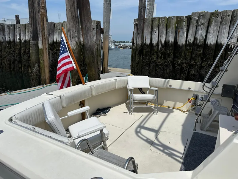Slide: The Image of 1985 Hatteras 36 Convertible boat with seating area and American flag at dock. - 3