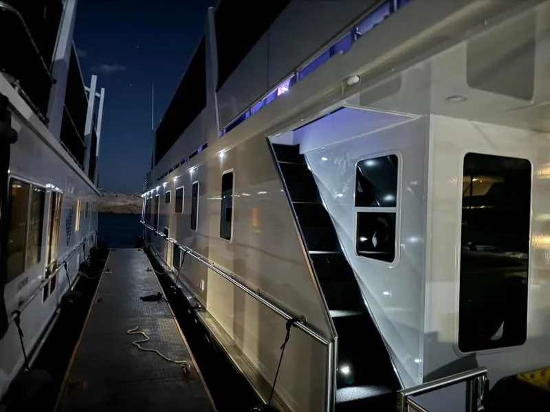 Slide: The Image of 2024 Sumerset Limitless Share 10 houseboat docked at night with illuminated exterior. - 2