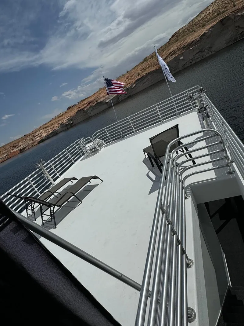 Slide: The Image of 2024 Sumerset Limitless Share 10 houseboat with spacious deck, lounge chairs, and scenic lake view. - 25