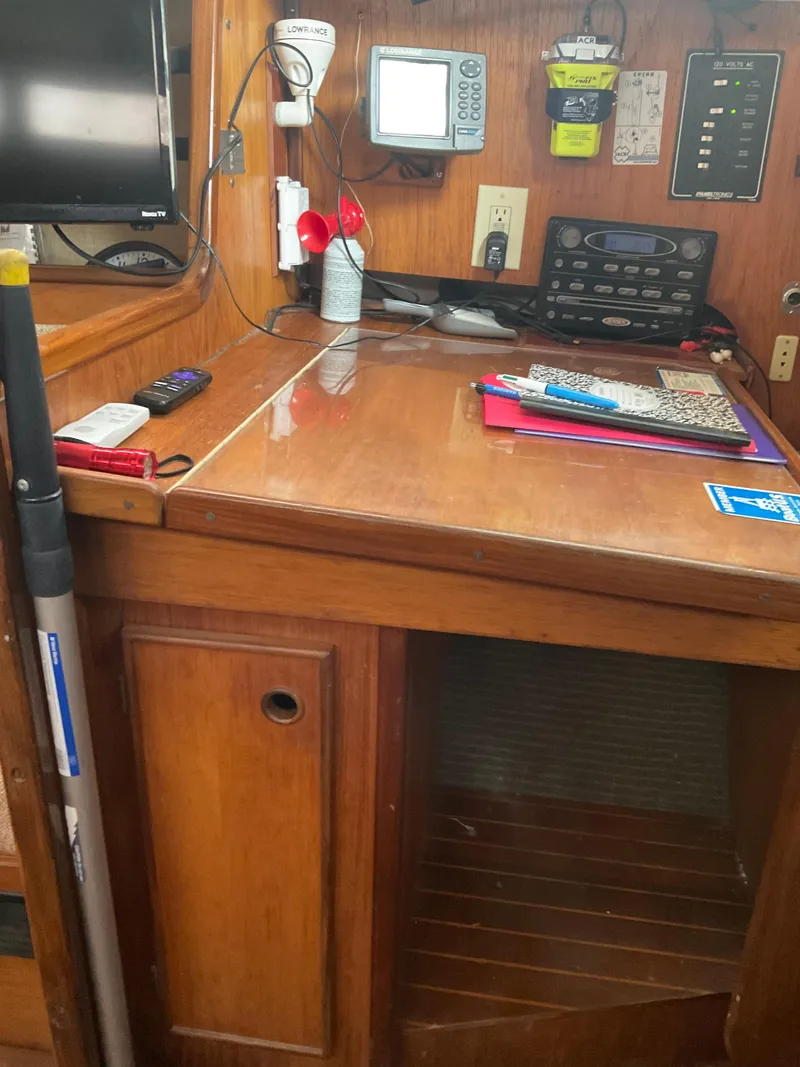 Slide: The Image of Navigation station inside a 1983 Jeanneau Attalia sailboat, featuring equipment and wooden cabinetry. - 12