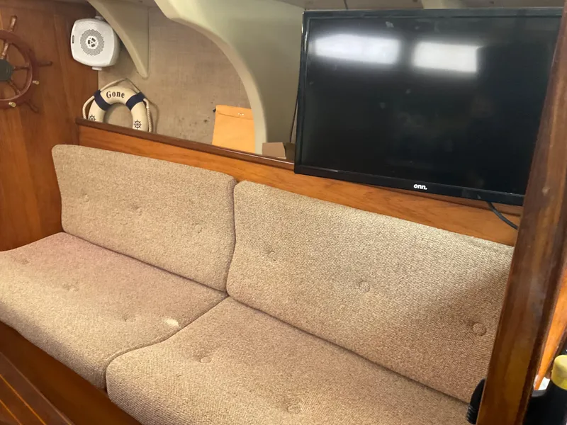 Slide: The Image of Interior of 1983 Jeanneau Attalia sailboat with beige sofa and mounted TV. - 13