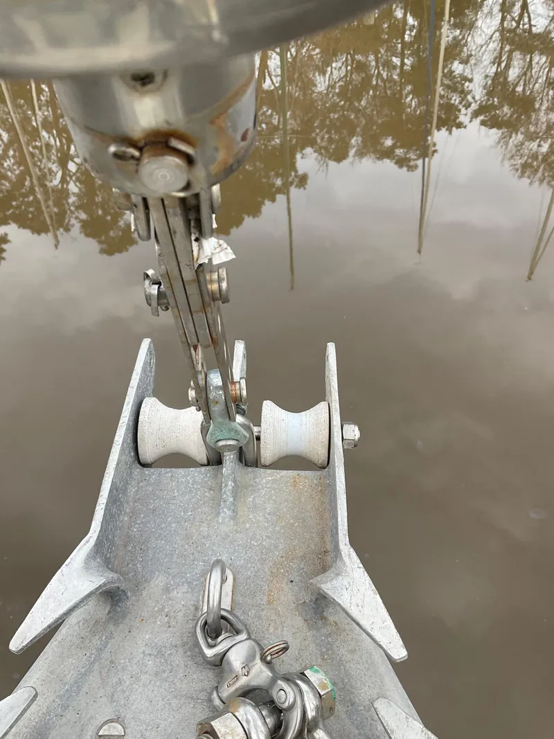 Slide: The Image of Anchor chain mechanism on a 1983 Jeanneau Attalia sailboat, reflecting in calm water. - 47