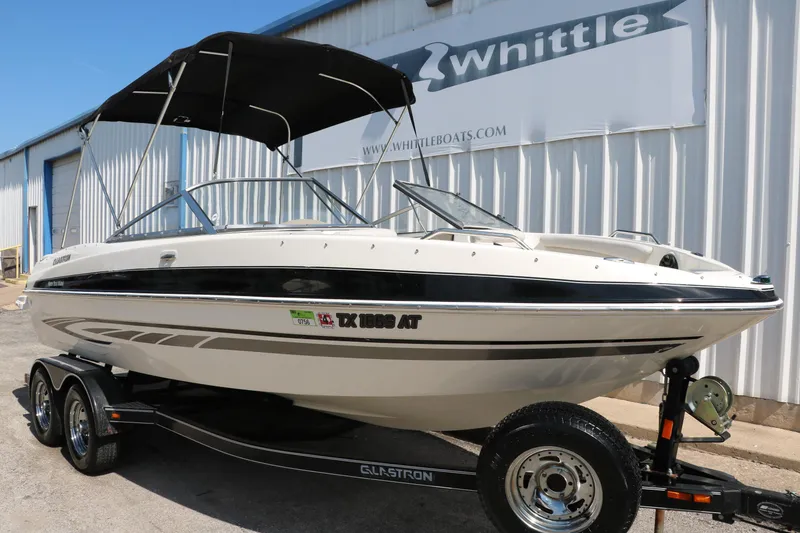Slide: The Image of 2008 Glastron GT225 boat with black bimini top on trailer outside Whittle Boats. - 15