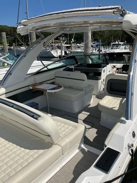 Slide: The Image of 2021 Cobalt 30SC Outboard boat interior with white seating and table, docked at marina. - 10