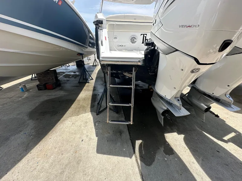 Slide: The Image of 2021 Cobalt 30SC Outboard boat with ladder and twin engines on a concrete surface. - 9