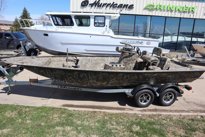 Slide: The Image of 2024 War Eagle 2170 Blackhawk boat on a trailer, parked outside a dealership. - 0