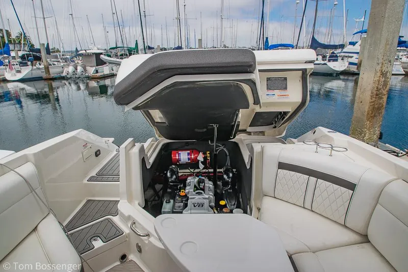 Slide: The Image of 2017 Sea Ray SLX 280 boat engine compartment open, docked at marina with sailboats. - 28