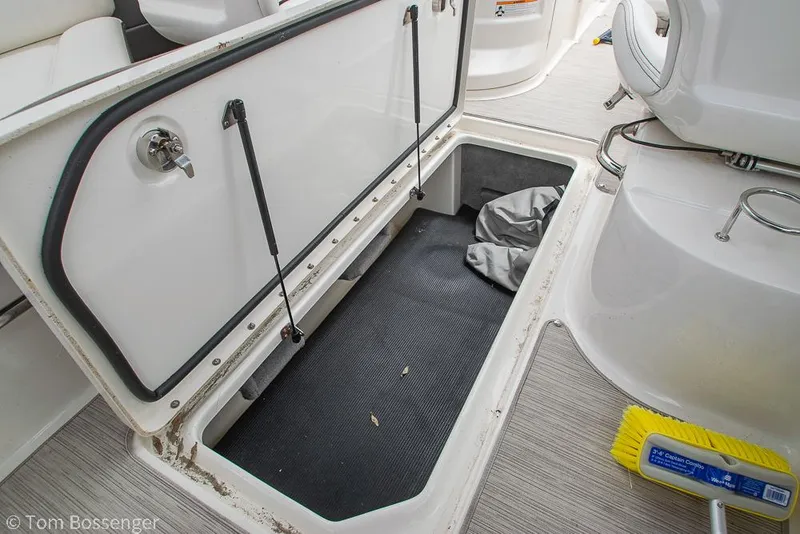 Slide: The Image of 2017 Sea Ray SLX 280 storage compartment with open hatch and cleaning brush. - 30