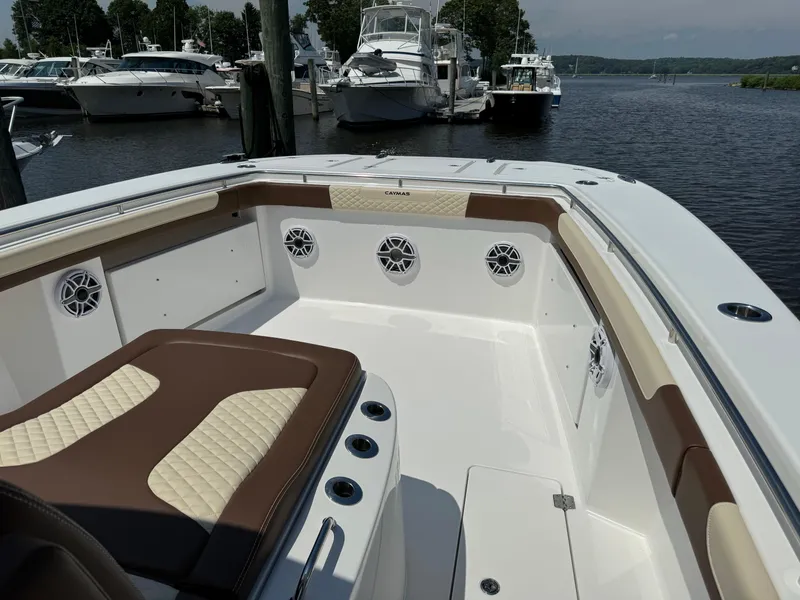 Slide: The Image of 2024 Caymas 34 CT boat interior with cushioned seating and speakers, docked at a marina. - 13