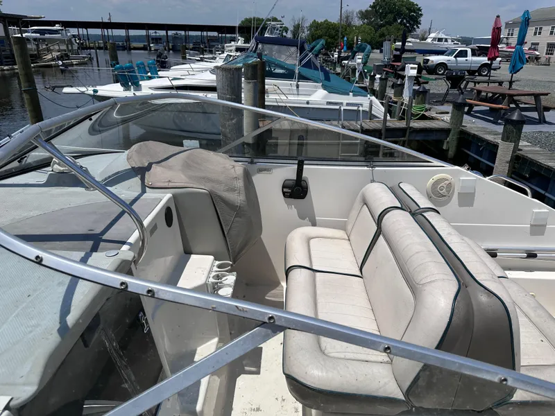Slide: The Image of 1996 Maxum 2400 SCR boat interior at a marina, featuring seating and control area. - 4