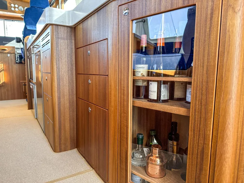 Slide: The Image of Luxurious wooden cabinetry in 2023 Targa 46 yacht interior, featuring a glass-fronted liquor cabinet. - 27