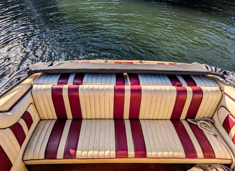 Slide: The Image of 1980 Tahiti Ocean Racer boat with red and white striped seating, docked on calm water. - 5