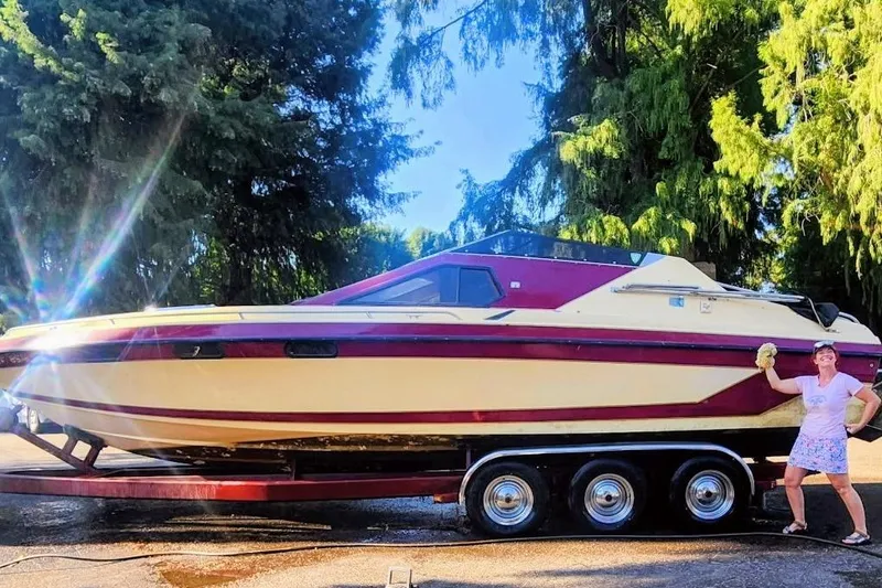 Slide: The Image of 1980 Tahiti Ocean Racer boat on trailer, person cleaning, surrounded by trees. - 7