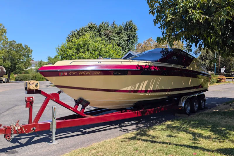 The Image of 1980 Tahiti Ocean Racer boat on trailer, parked outdoors under trees. - 0