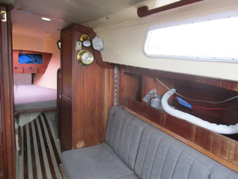 Slide: The Image of 1979 CAL 31 sailboat interior with wood paneling, gray seating, and cozy cabin layout. - 12