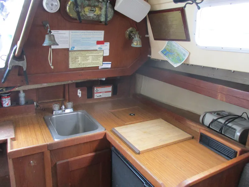 Slide: The Image of 1979 CAL 31 sailboat interior kitchen with sink, cutting board, and nautical decor. - 14