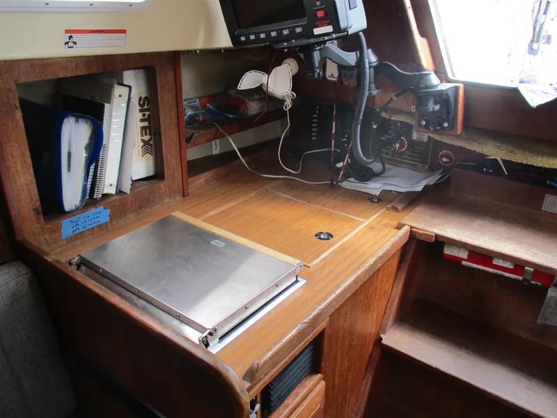Slide: The Image of 1979 CAL 31 sailboat navigation station with equipment, books, and wooden cabinetry. - 15