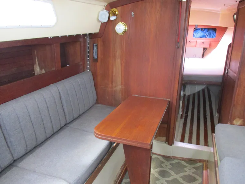 Slide: The Image of Interior of a 1979 CAL 31 sailboat with wooden table and cushioned seating. - 19
