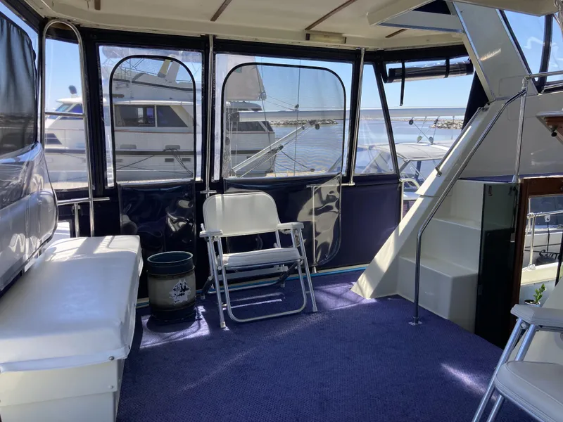 Slide: The Image of 1987 Tollycraft 44 Cockpit Motor Yacht interior with seating and stairs, docked at marina. - 11