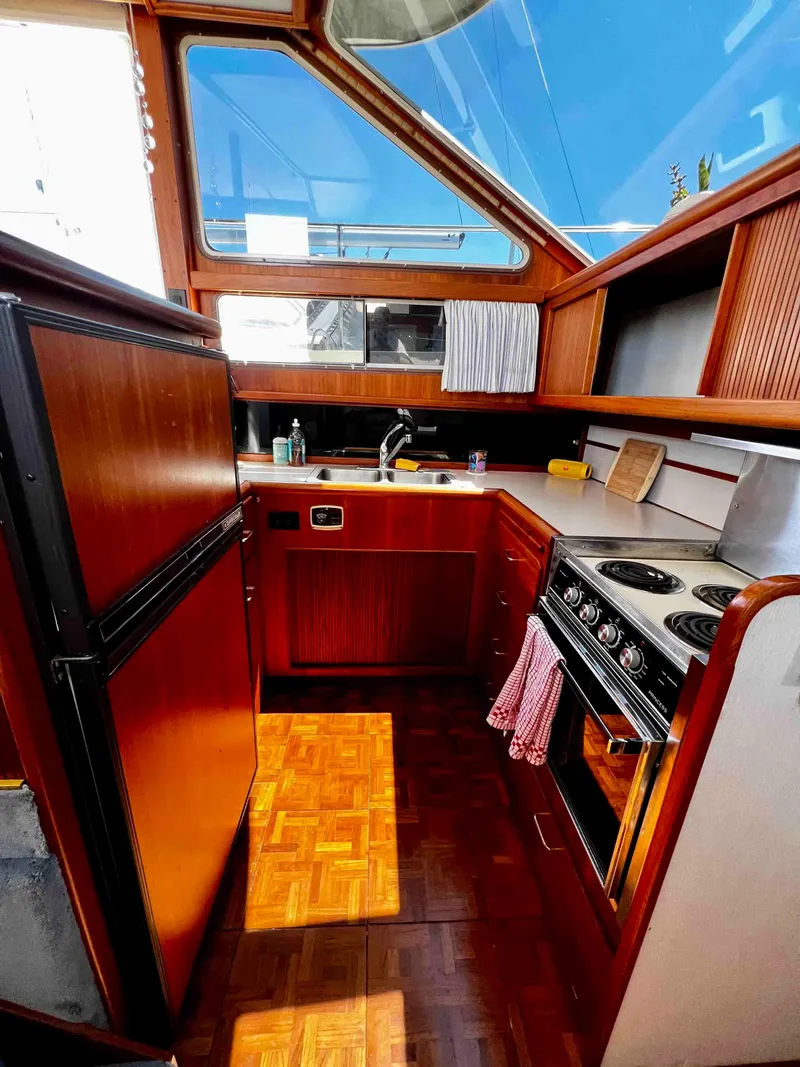 Slide: The Image of 1987 Tollycraft 44 Cockpit Motoryacht kitchen with wood cabinetry and modern appliances. - 29