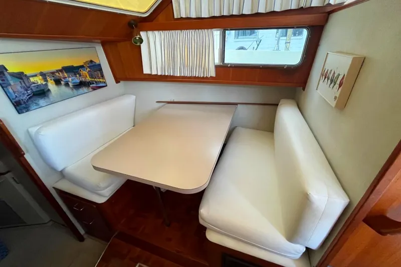 Slide: The Image of 1987 Tollycraft 44 Cockpit Motor Yacht interior with white seating and dining table. - 32