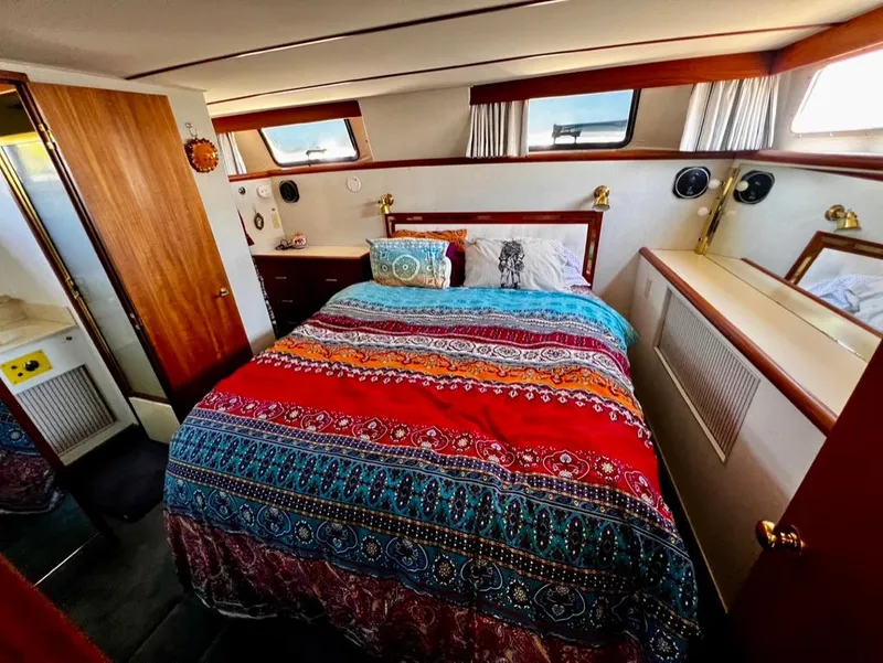 Slide: The Image of 1987 Tollycraft 44 Cockpit Motoryacht bedroom with colorful bedding and wooden accents. - 37