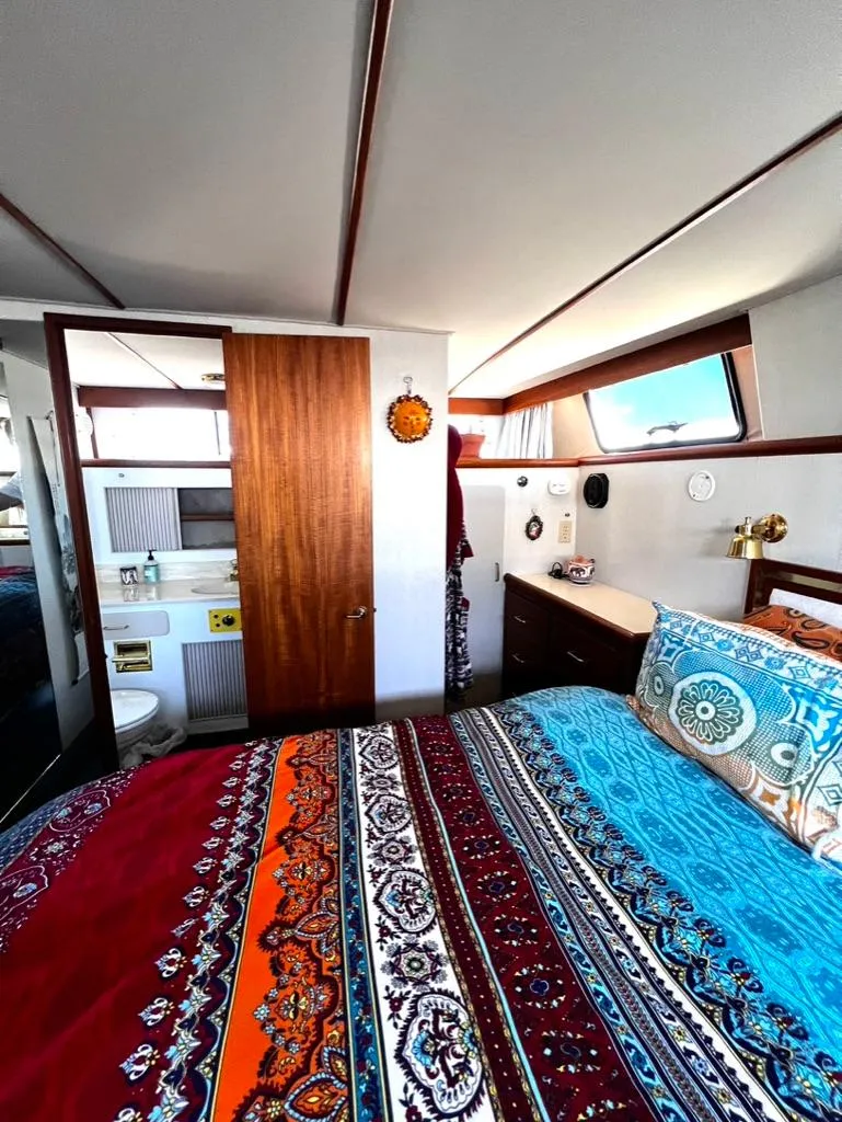Slide: The Image of 1987 Tollycraft 44 Cockpit Motoryacht bedroom with colorful bedding and ensuite bathroom. - 38