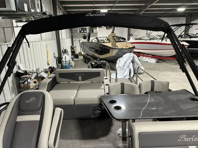 Slide: The Image of 2025 Barletta Boats Cabrio C24UE interior in a showroom, featuring seating and table. - 31