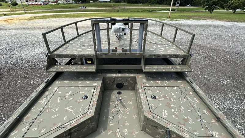 Slide: The Image of 2024 Tracker Grizzly 2072 CC SportMan boat with camo deck and railing, parked outdoors. - 12