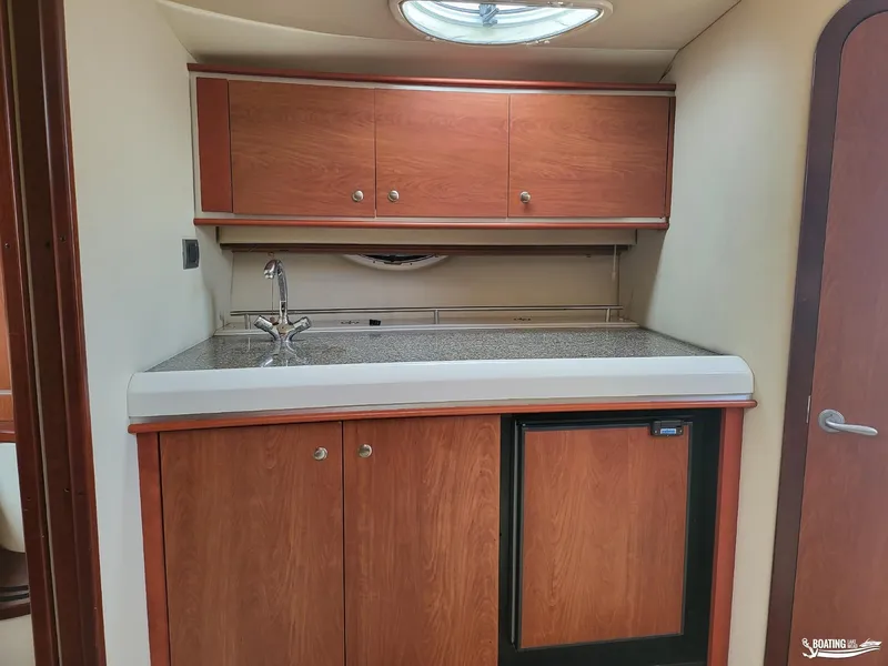 Slide: The Image of 2008 Monterey 350 Sport Yacht interior kitchen with wood cabinets and compact fridge. - 26